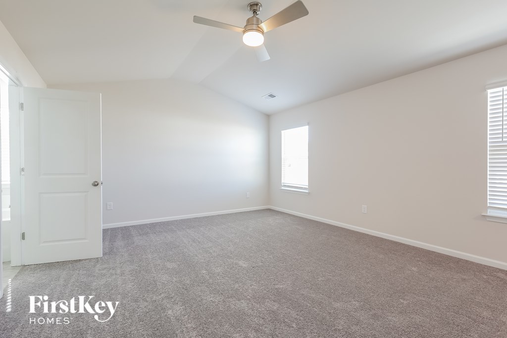 A spacious room with a ceiling fan and a door.