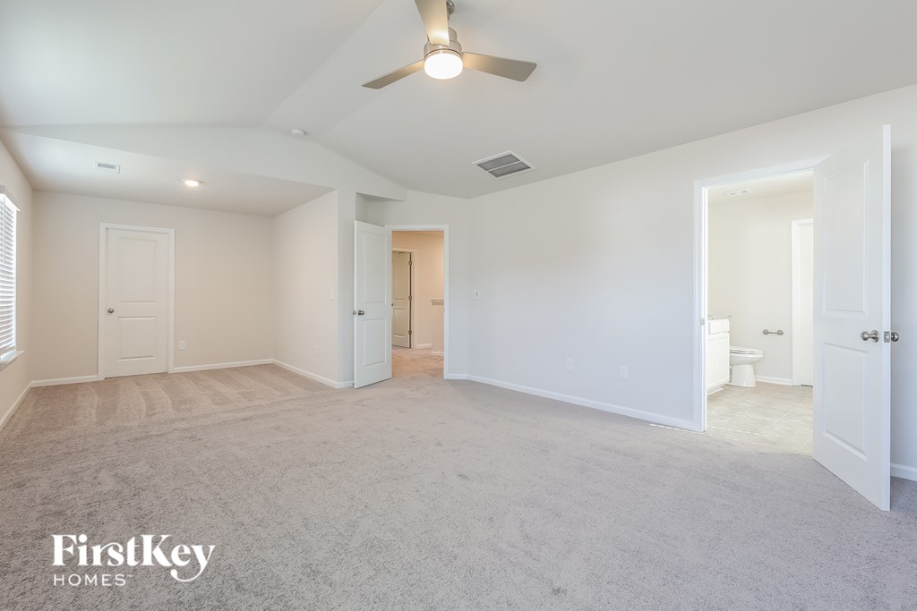 A spacious room with a ceiling fan and a carpeted floor.