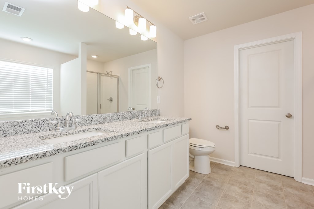 A bathroom with a granite countertop and a white toilet.