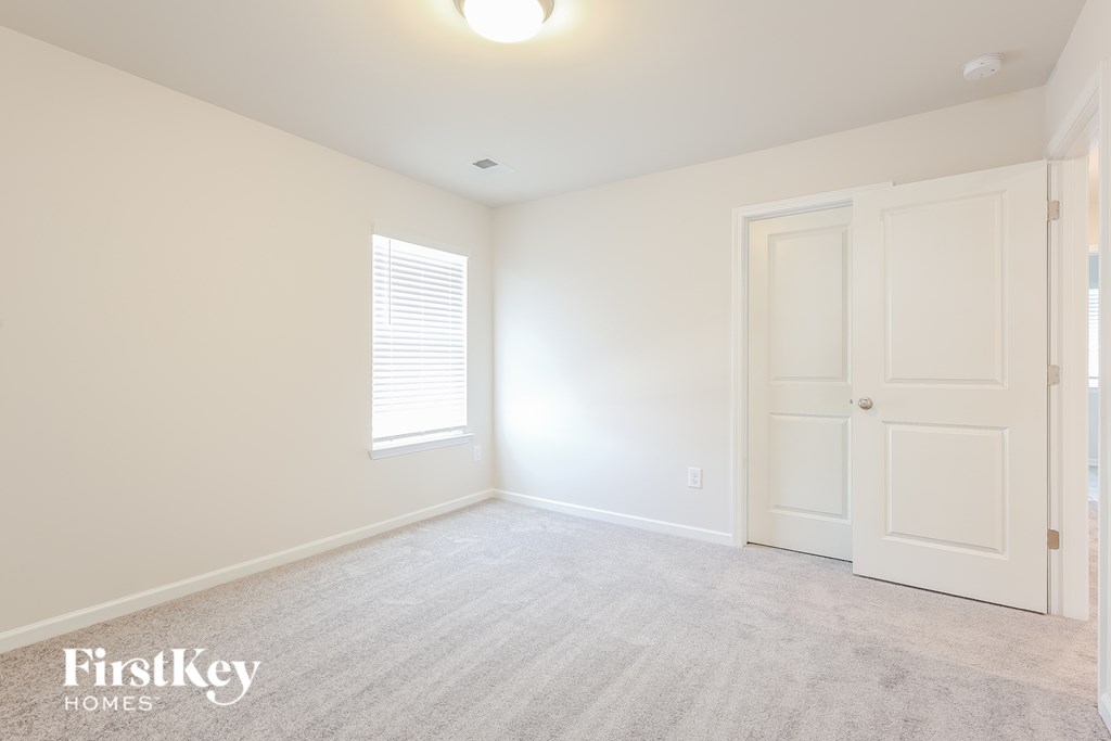 A room with a white door and a window with blinds.