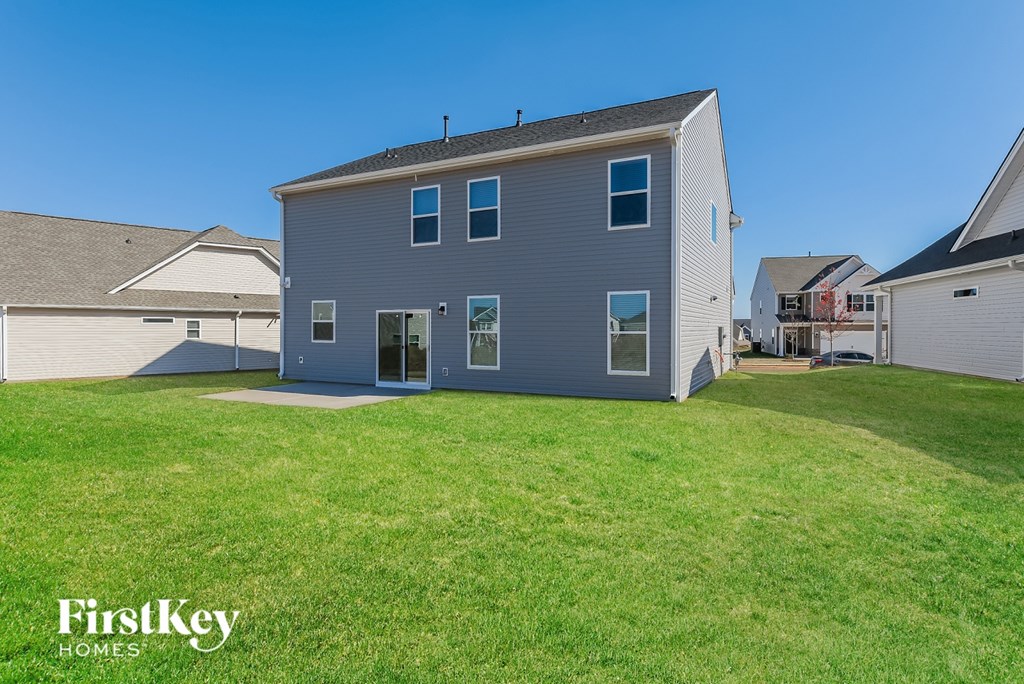 A grey house with a white roof and a green lawn in front.