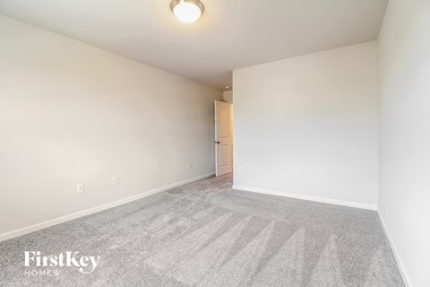 a spacious living room with carpet and white walls