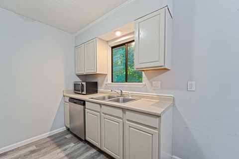 a kitchen with white cabinets and a sink and a window