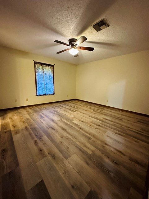 an empty living room with wooden floors and a ceiling fan