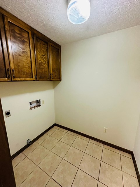 a room with a tile floor and white walls and wooden cabinets