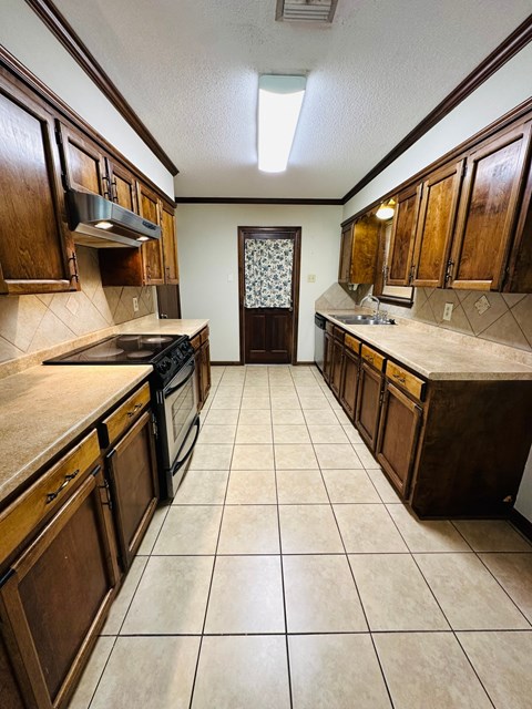 a kitchen with wooden cabinets and tiled floors