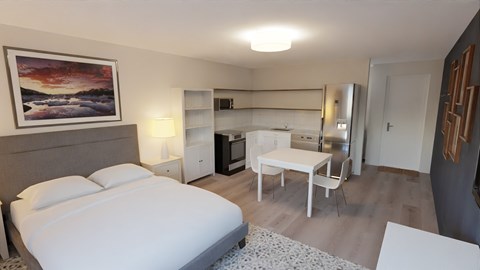 a bedroom with a bed and a desk and a kitchen