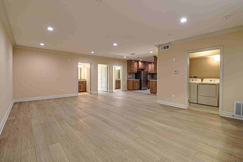 an empty living room with a kitchen in the background