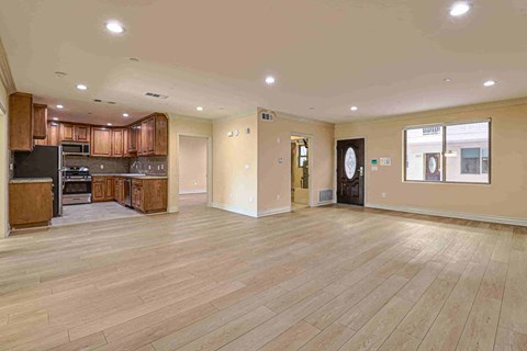 an empty living room and kitchen with wood flooring