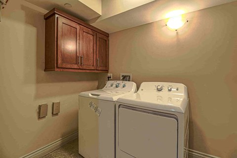 a full size washer and dryer in a laundry room with wooden cabinets