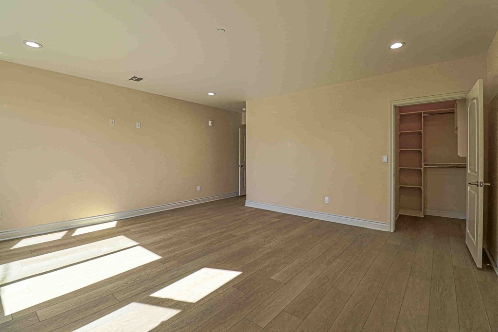 an empty living room with wooden floors and a closet