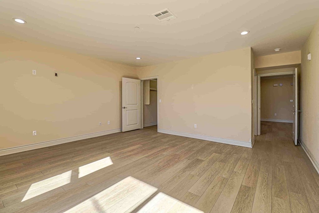 an empty living room with wood floors and a door to a hallway