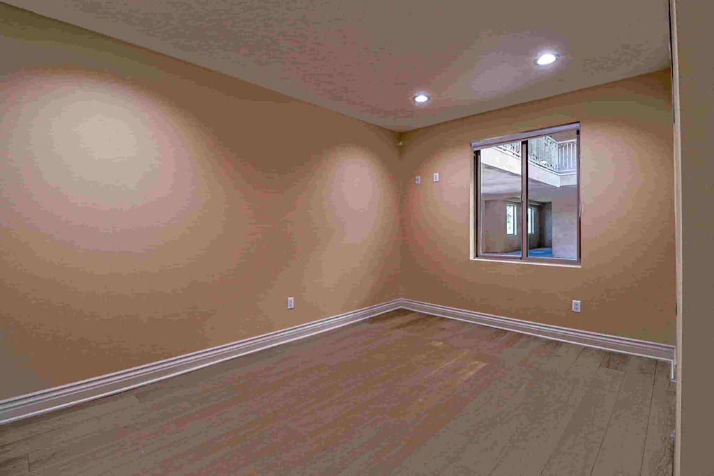 a bedroom with a hardwood floor and a window