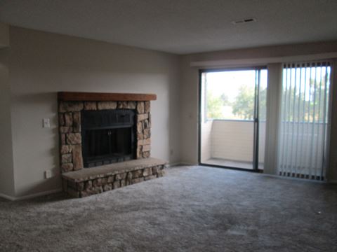 an empty living room with a fireplace and a sliding glass door