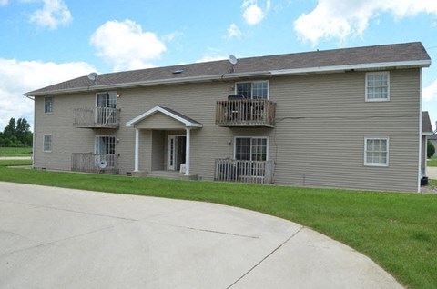 a beige house with two balconies and a sidewalk