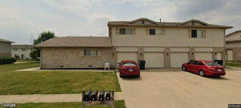 A house with two red cars parked in front.