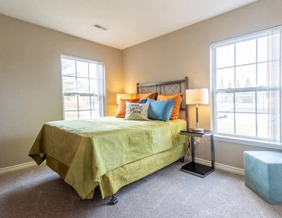 a bedroom with a bed and two windows