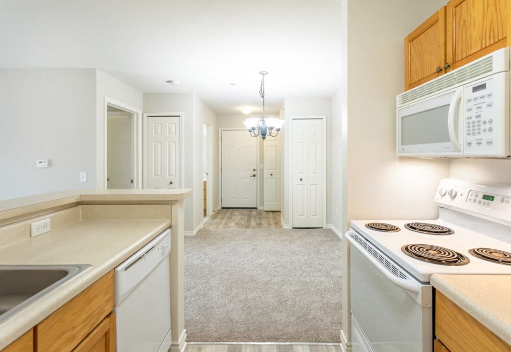 a kitchen with white appliances and wooden cabinets and a white microwave