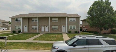 A two-story house with a white car parked in front.