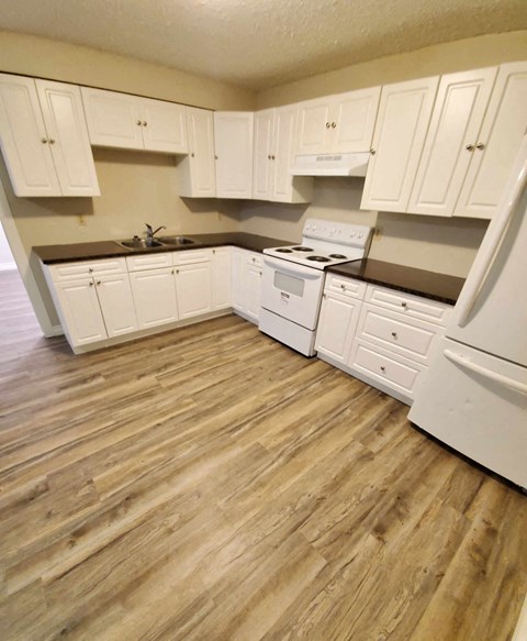 a kitchen with white cabinets and a wooden floor