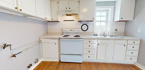 A white kitchen with wood floors and white appliances.