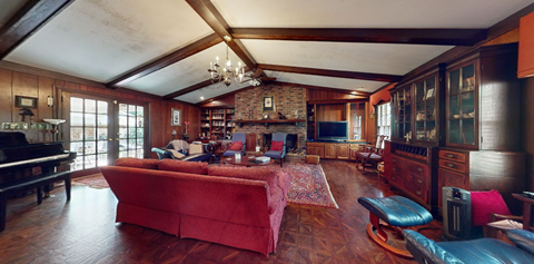 A living room with a red couch and a piano.