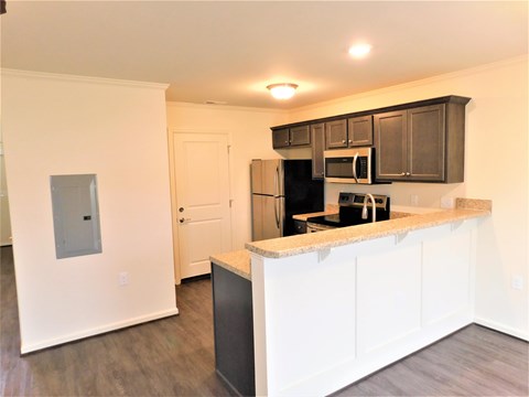 A kitchen with white cabinets and a black refrigerator.