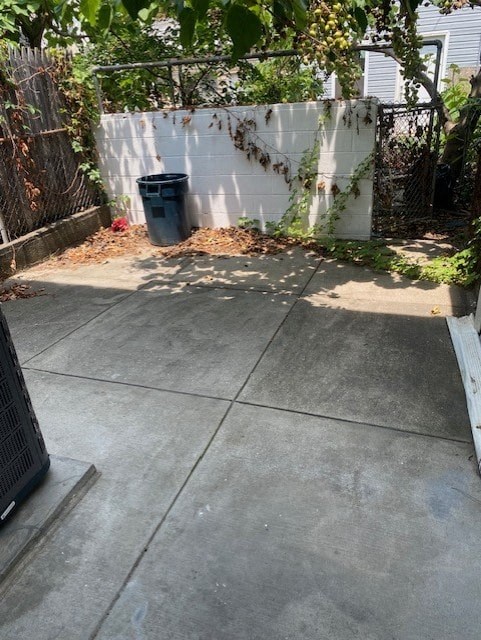 a driveway with a trash can in front of a fence
