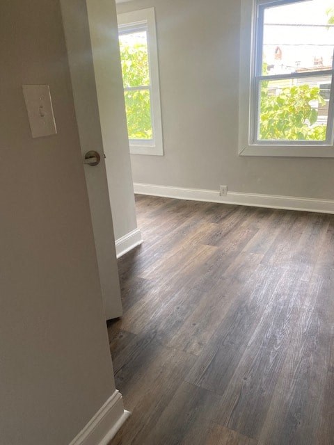 an empty room with a hard wood floor and two windows