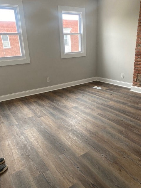 an empty room with wooden floors and two windows