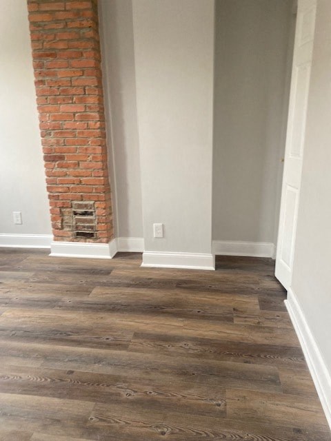 an empty room with wooden floors and a brick wall