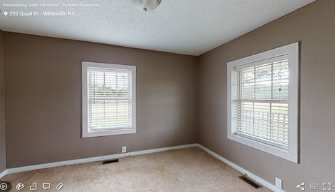 a bedroom with two windows and a carpeted floor