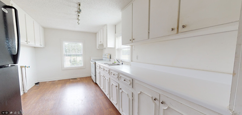 a large white kitchen with white cabinets and wood floors