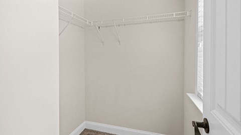 an empty closet in a bedroom with white walls and a window