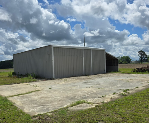 A large grey building with a metal roof and a small antenna on top.