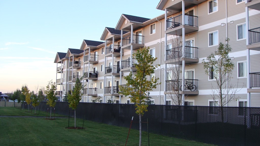 an exterior view of an apartment building with trees in front of it