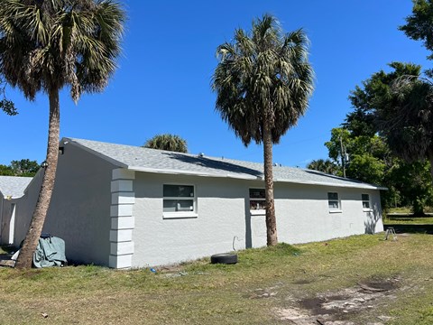a small white house with two palm trees