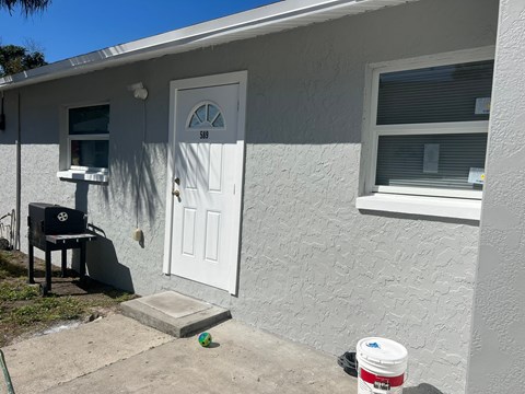the side of a house with a white door and a grill