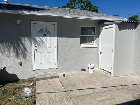 the exterior of a white house with a white door and a driveway