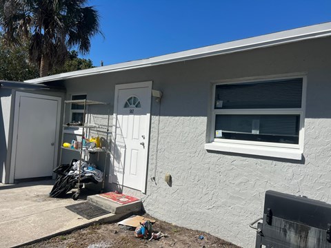 a view of the outside of a house with a grill and a window