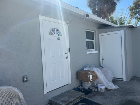 a white house with a white door and a window and some trash