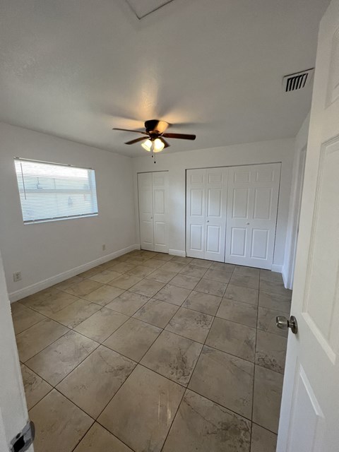 an empty living room with a ceiling fan and tiled floor