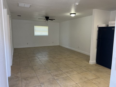 an empty living room with tile floors and a ceiling fan