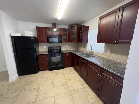 A kitchen with brown cabinets and black appliances.