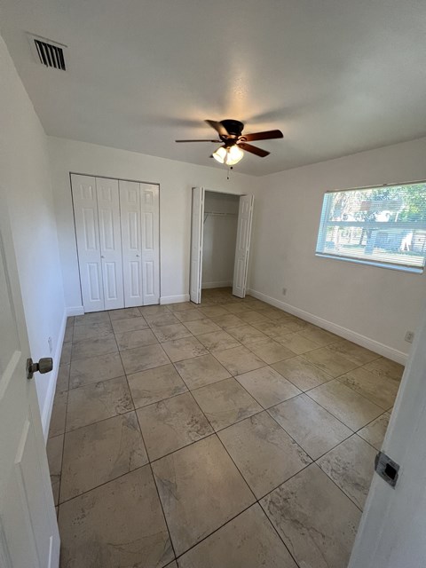 an empty living room with a ceiling fan and tiled floors