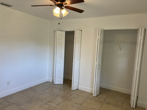 a room with a ceiling fan and two closet doors