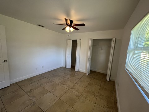 an empty living room with a ceiling fan and a closet