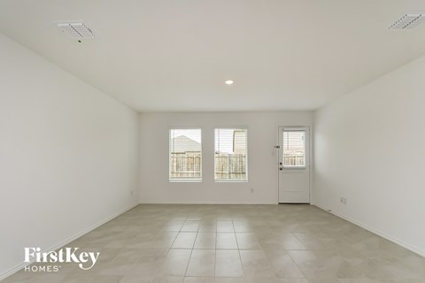 a spacious living room with white walls and tile floors