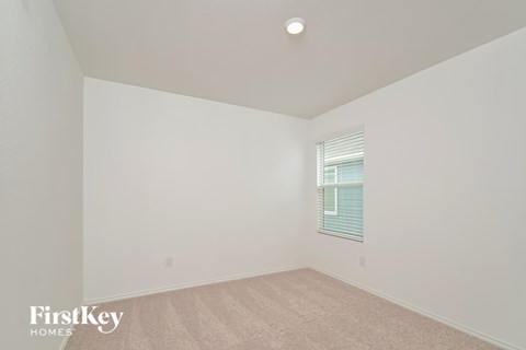a bedroom with white walls and carpet and a window