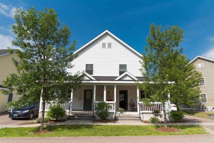 A house with a white front porch and a tree in front.